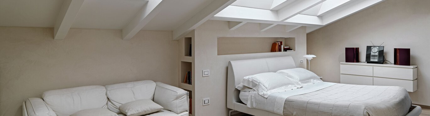 Ein Schlafzimmer mit drei Dachfenstern.