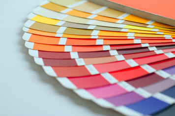 Mehrere Papierstreifen in unterschiedlichen Farben, welche das Farbensortiment bei Rollos darstellt.