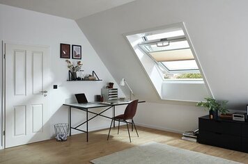 Ein Zimmer mit einem Dachfenster welches mit Faltstoren ausgestattet ist. 