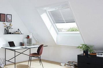 Ein Zimmer mit Dachfenster welches mit Jalousetten ausgestattet ist. 