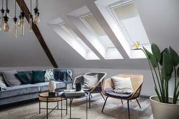 Ein Zimmer mit drei Dachfenstern an denen Rollos angebracht sind, die den Raum abdunkeln.